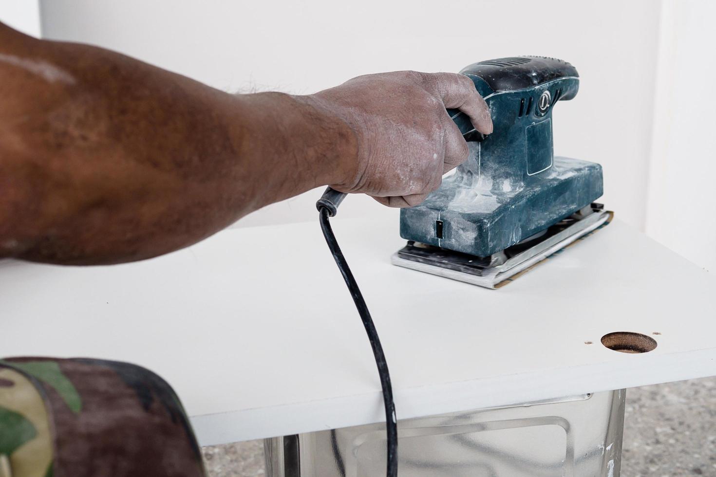 schilder werkt aan het schilderen van meubels met behulp van een schrobmachine die een gladde en schone oppervlaktekleur maakt - timmerman werkt met handgereedschapconcept foto