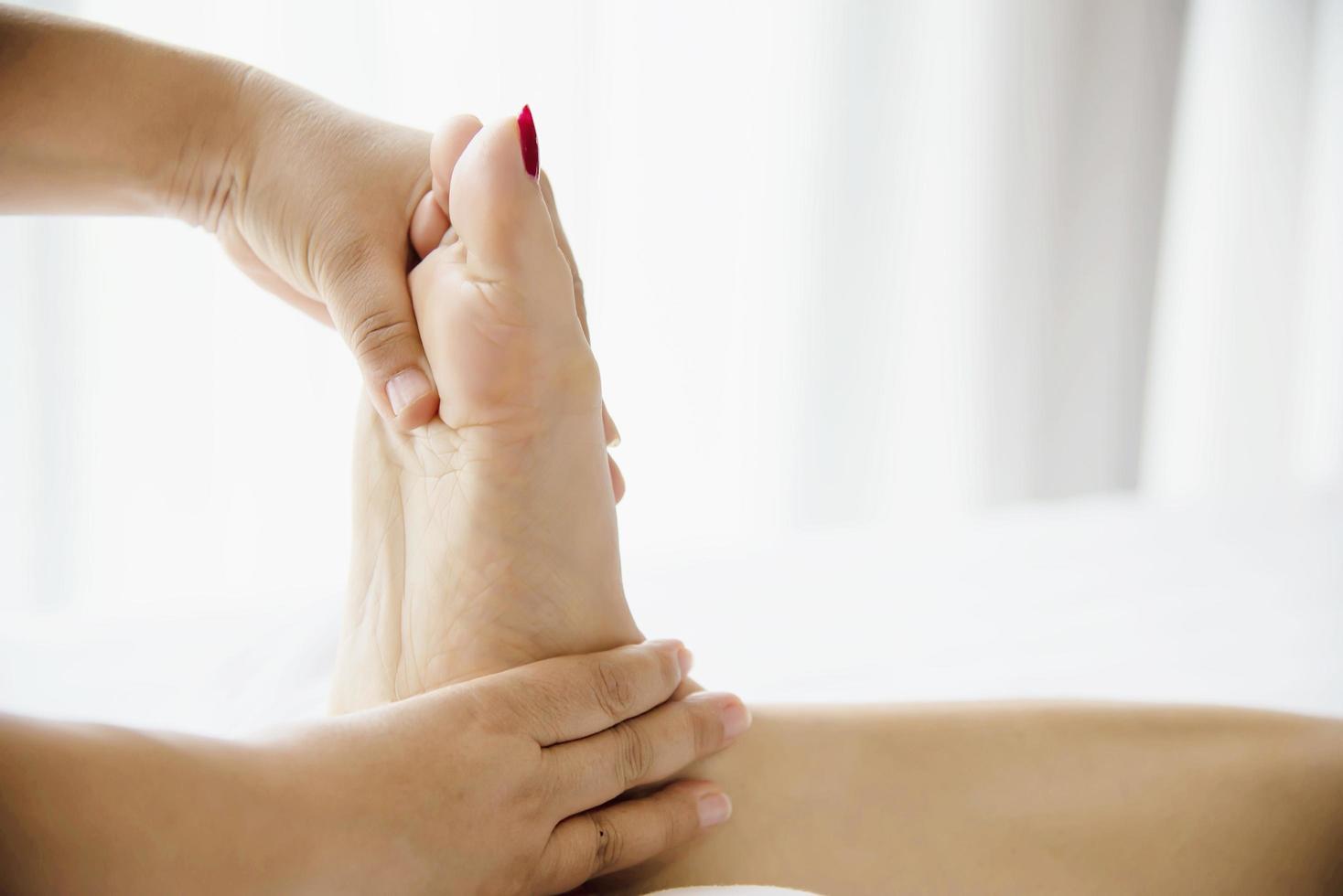 vrouw die voetmassage krijgt van masseuse close-up bij hand en voet - ontspan in voetmassage therapie dienstverleningsconcept foto