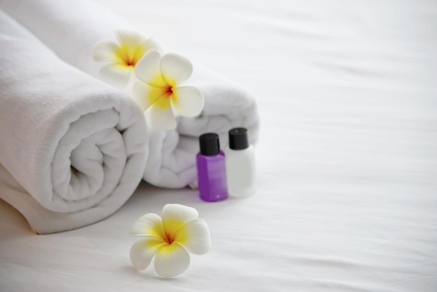 hotelhanddoek en shampoo en zeepbadfles op wit bed met versierde plumeriabloem - ontspan vakantie in het concept van het hotelresort foto
