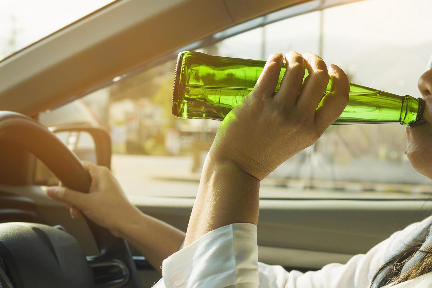 vrouw die bier drinkt tijdens het autorijden foto