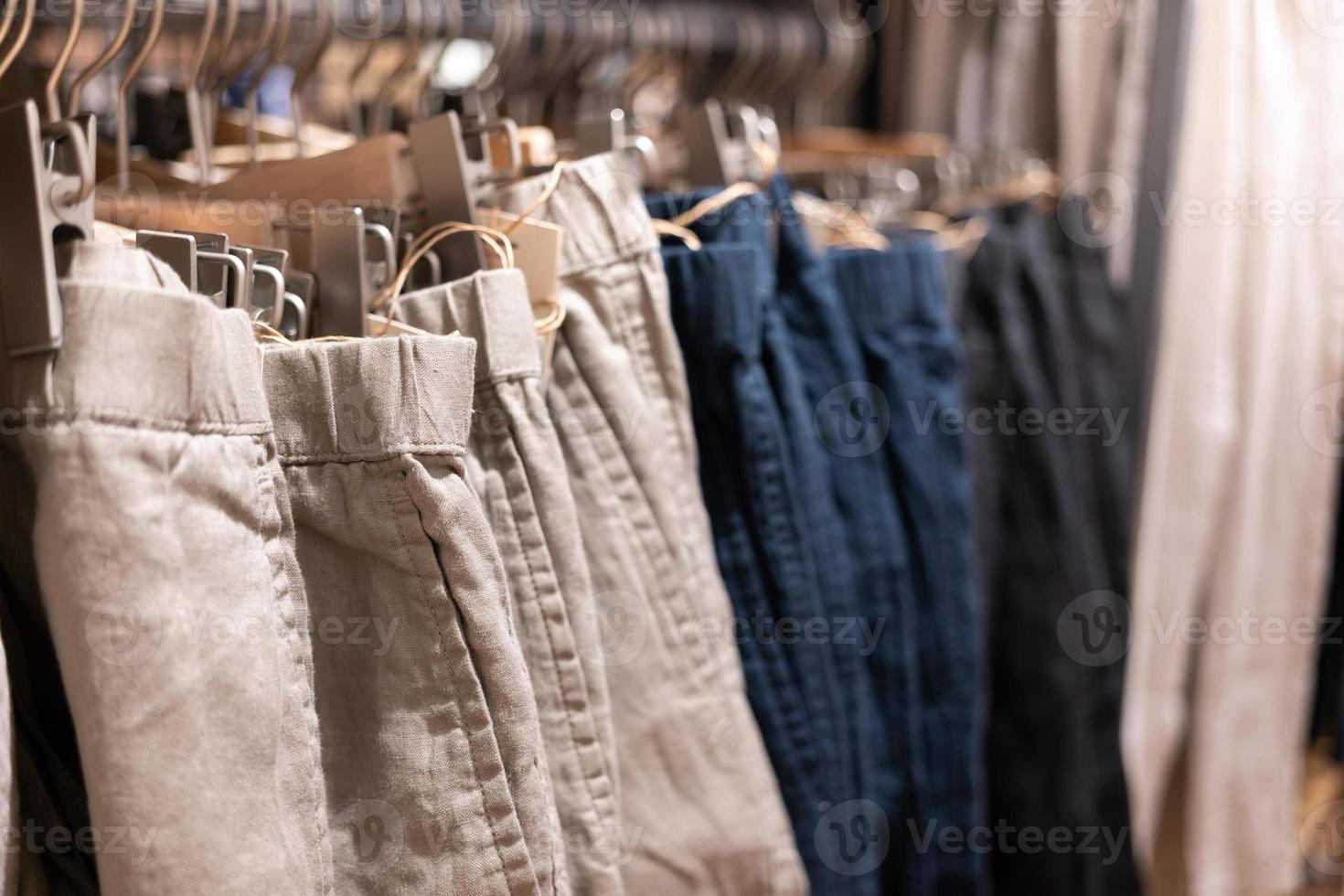 selectieve focus, mode, kledingconcept, kleding of broek veel kleuren hangen op een plank in een merkkledingwinkel. veel pastelkleurig foto
