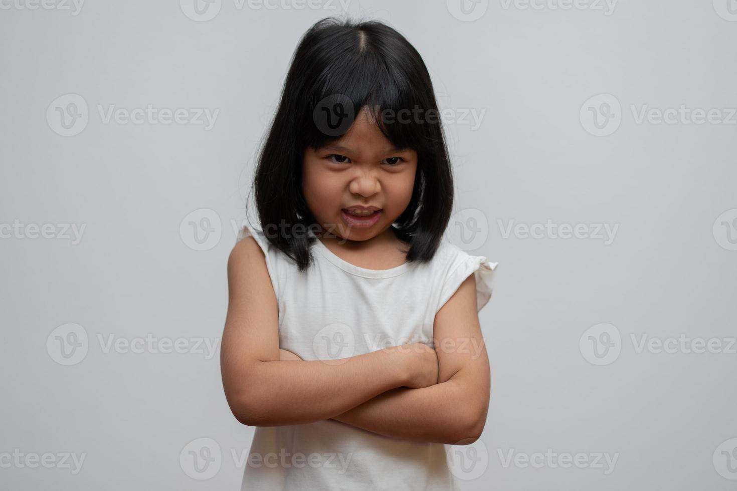portret van Aziatische boos en verdrietig meisje op een witte geïsoleerde achtergrond, de emotie van een kind wanneer driftbui en boos, expressie knorrige emotie. kind emotionele controle concept foto