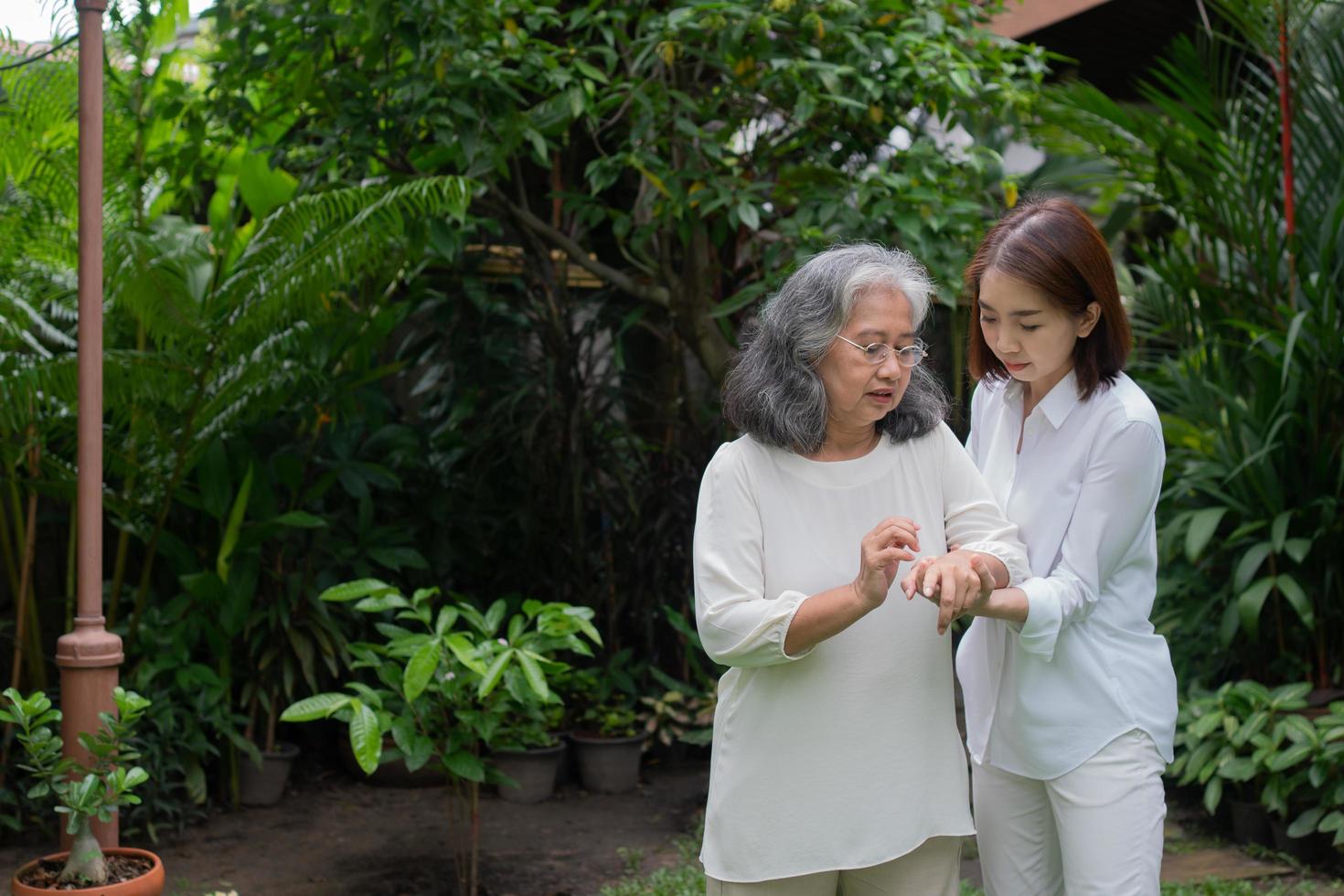 een oude bejaarde aziatische vrouw en wandelen in de achtertuin met haar dochter. concept van gelukkig pensioen met zorg van een verzorger en spaar- en senior ziektekostenverzekering, gelukkig gezin foto
