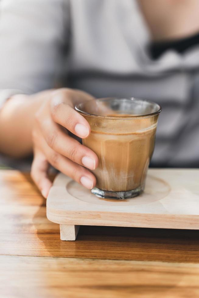 vrouw houdt een glas espresso geschoten over koude verse melk. vuile koffie, koffiemenu, melkkoffie foto