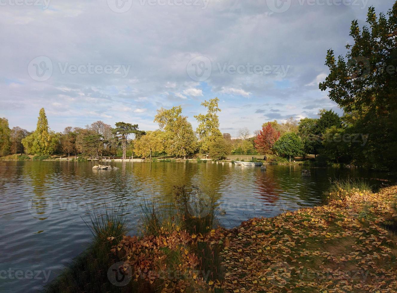 zonnige herfst, dag in het park bij het meer, natuurlijke achtergrond, helder wateroppervlak met reflectie van bomen, gele bladeren op de vervaagde grasgrond, vincennes bos in parijs foto