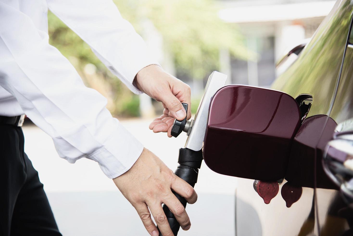 man zet ngv, aardgasvoertuig, hoofddispenser naar een auto bij het benzinestation in thailand foto