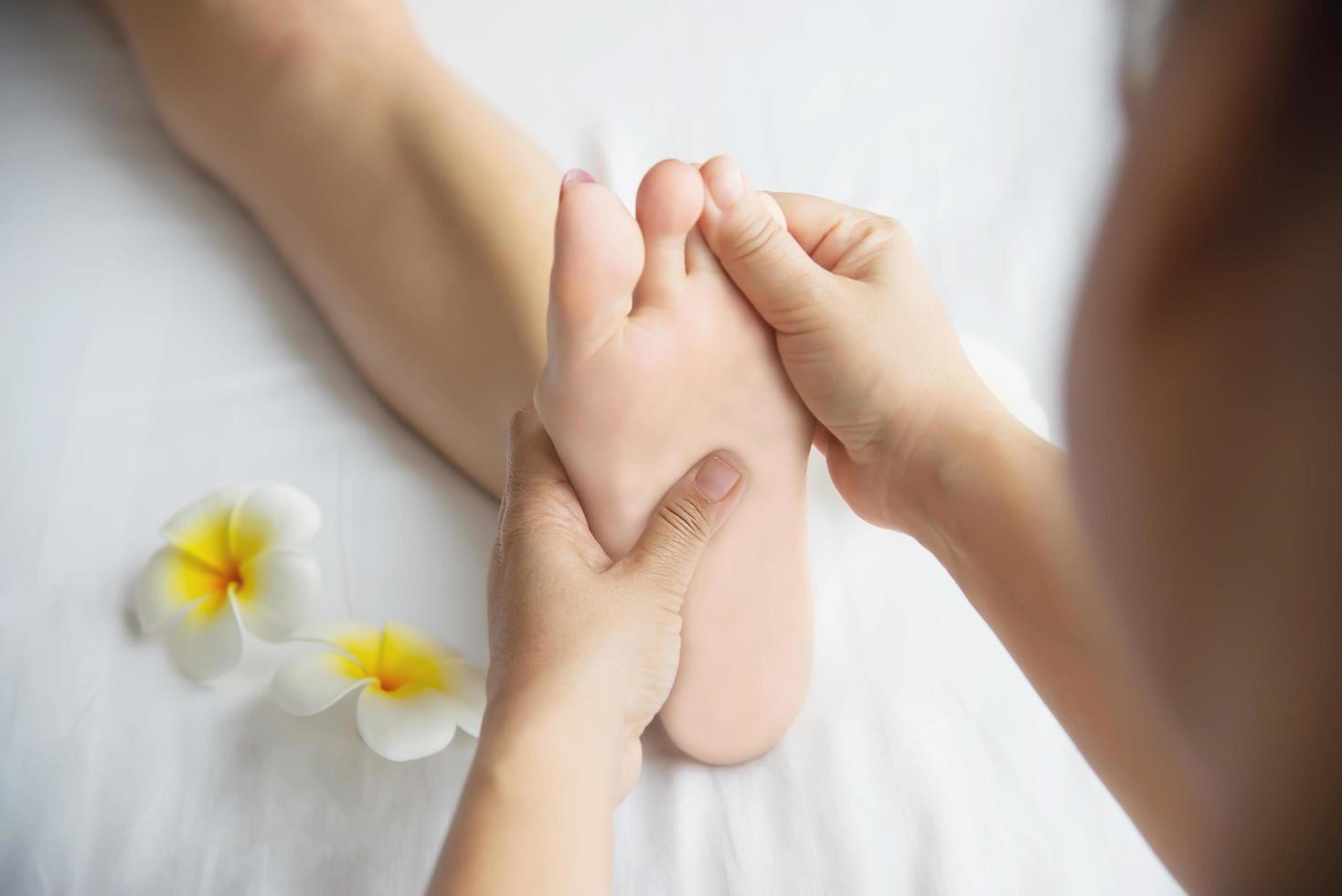 vrouw die voetmassage krijgt van masseuse close-up bij hand en voet - ontspan in voetmassage therapie dienstverleningsconcept foto