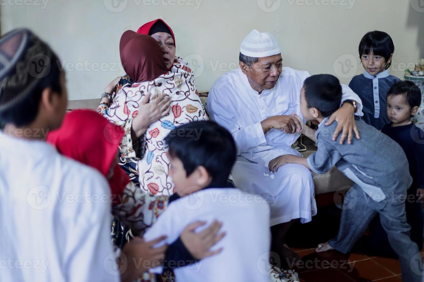 lebaran thuiskomst in de geboorteplaats begroeten elkaar en verontschuldigen zich tijdens de eid. familie omhelzen elkaar, grootouders met kleinkinderen. familiebijeenkomst concept. foto