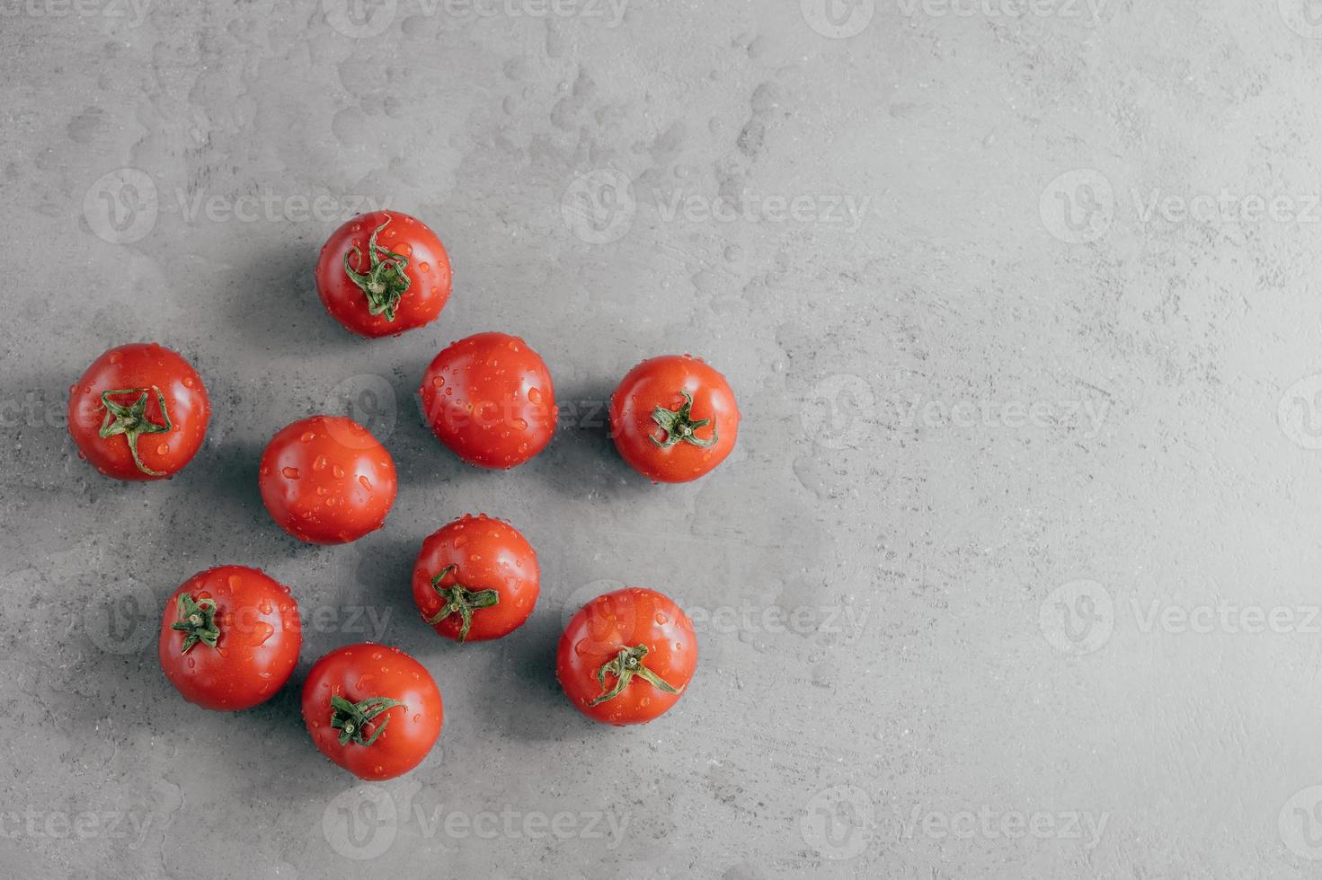 verse rode tomaten met waterdruppels geïsoleerd over grijze achtergrond met kopie ruimte. natuurlijke biologische voeding met vitamines foto