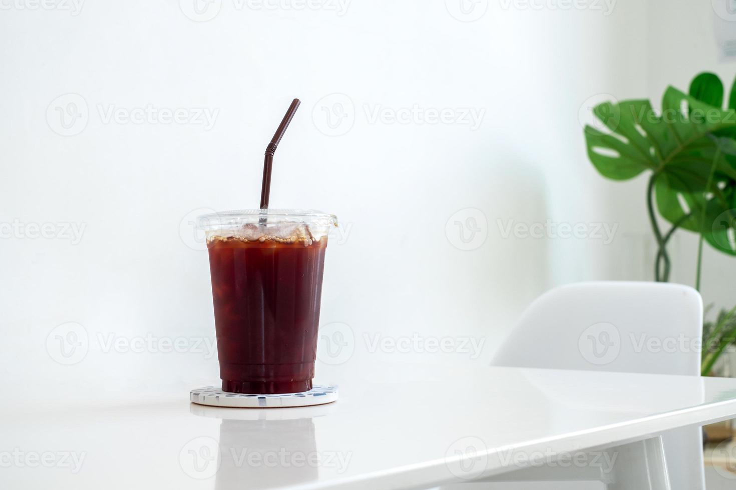 zwarte koffie, americano-koffie in plastic koffiekopje op witte tafel in coffeeshop, concept voor eten, drinken en gezondheid, kopieerruimte foto