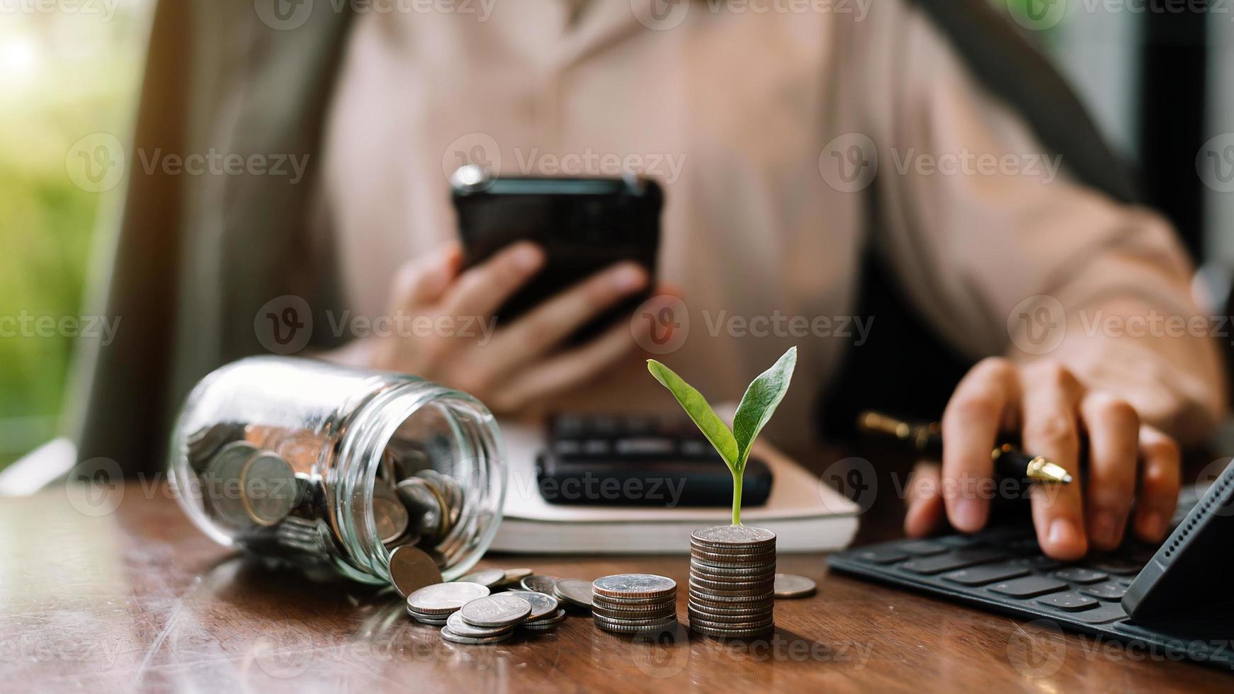 zakenvrouw stapelen munten met plant groeit op en gebruik rekenmachine.save en investeringsconcept .finance en bespaar geld foto