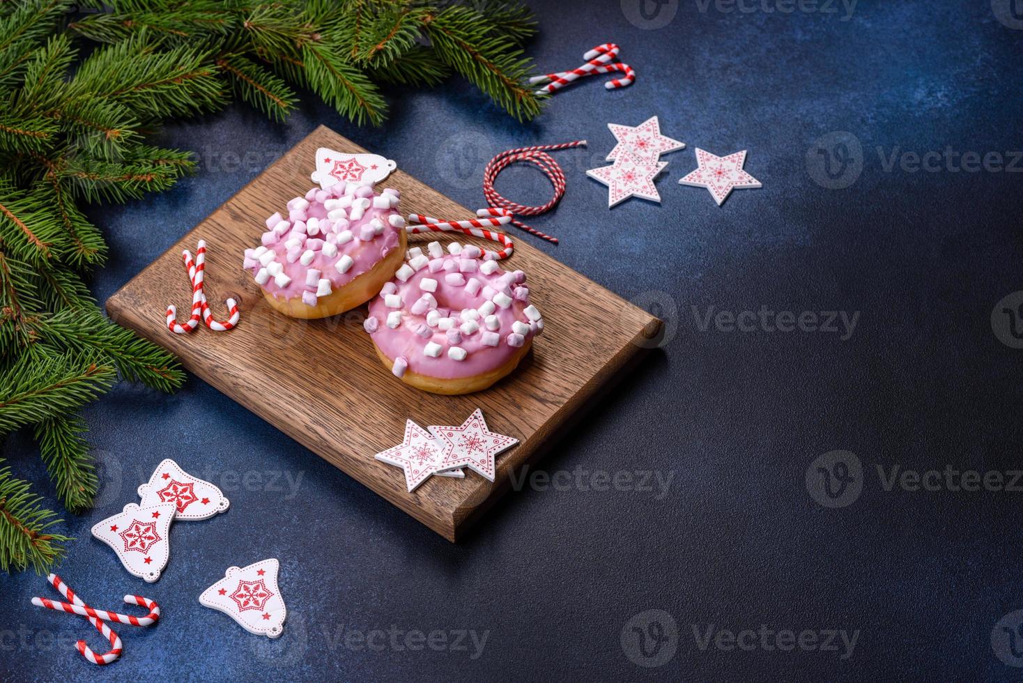 roze geglazuurde donut en marshmallow met kerstversiering op een houten snijplank foto