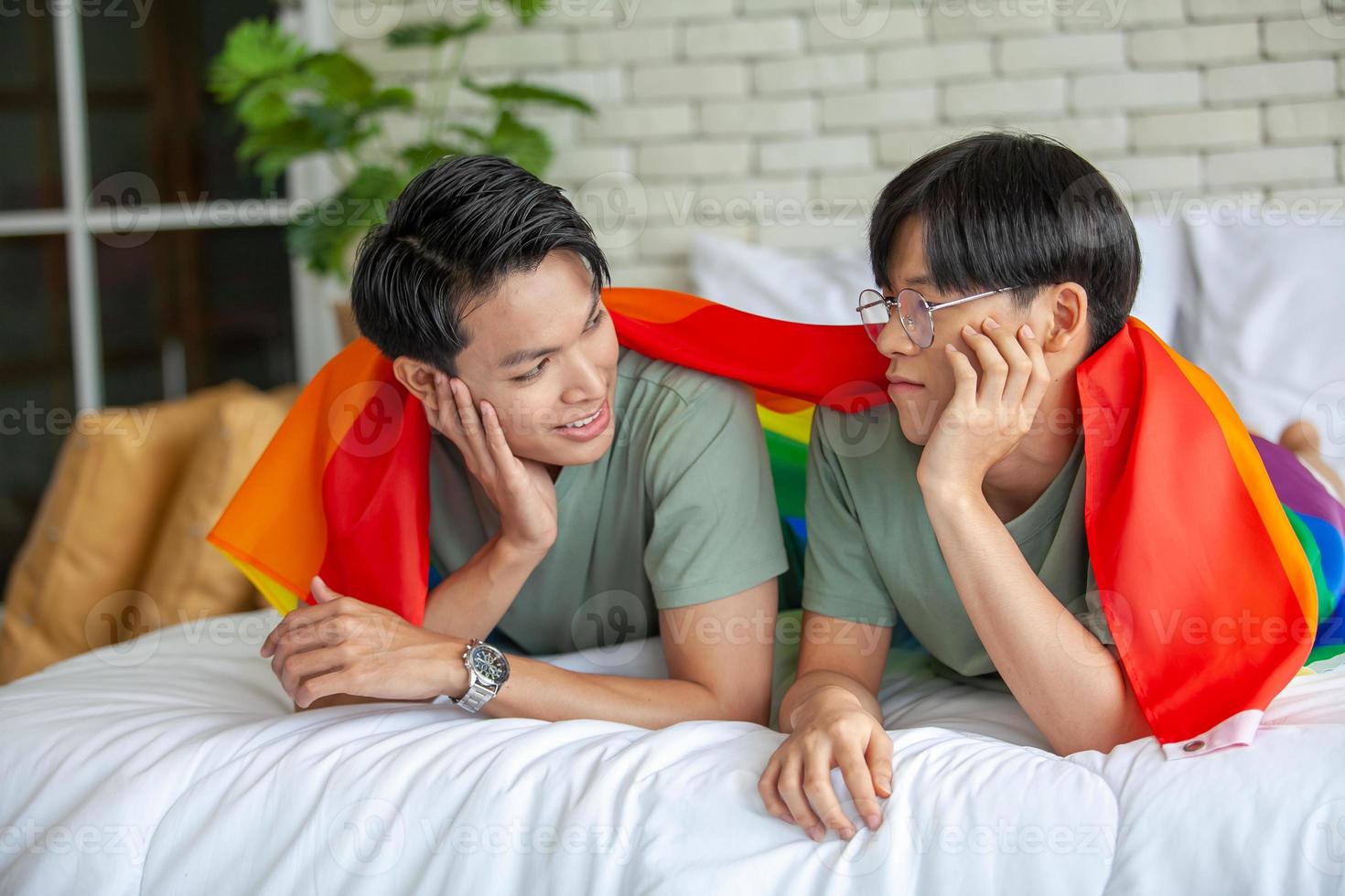 gelukkig aziatisch homopaar dat samen praat en thuis ontspant op bed, lgbtq-concept. foto