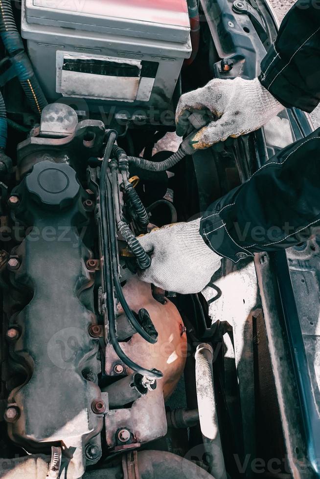 automonteur repareert automotor. man's handen in werkhandschoenen close-up. diagnostiek en restauratie van oude onderdelen. vervanging van hoogspanningsdraden. foto