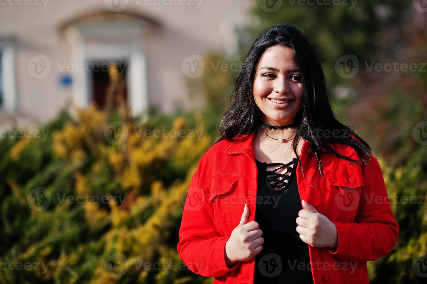 mooie latino model meisje uit ecuador slijtage op zwarte en rode jas gesteld op straat. foto