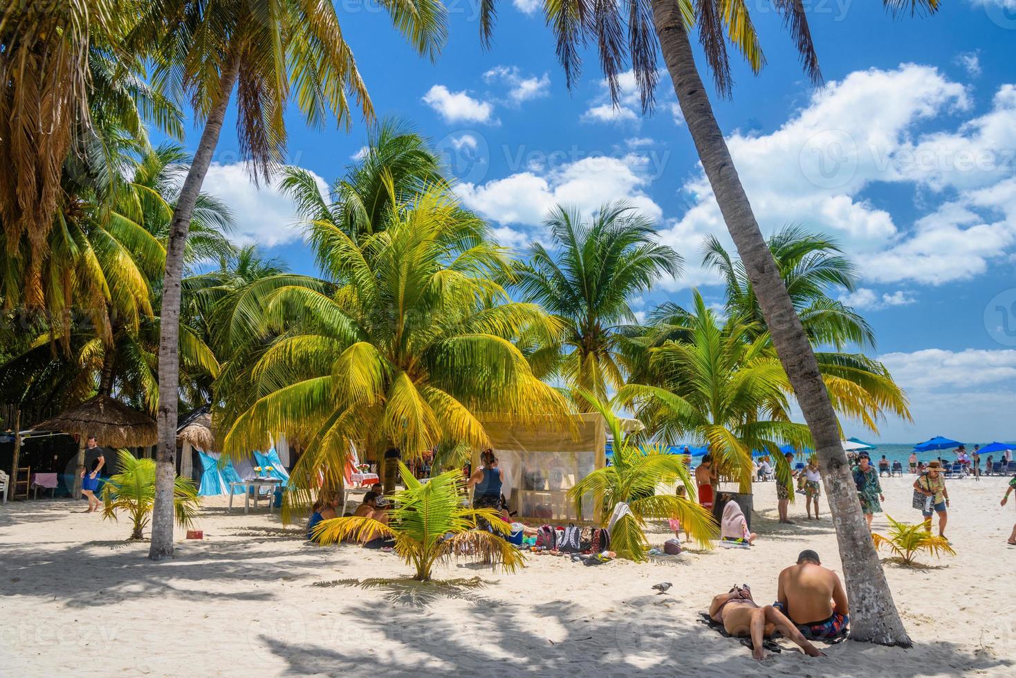 mensen zonnebaden in de schaduw van kokospalmen op het witte zandstrand, het eiland isla mujeres, de caribische zee, cancun, yucatan, mexico foto