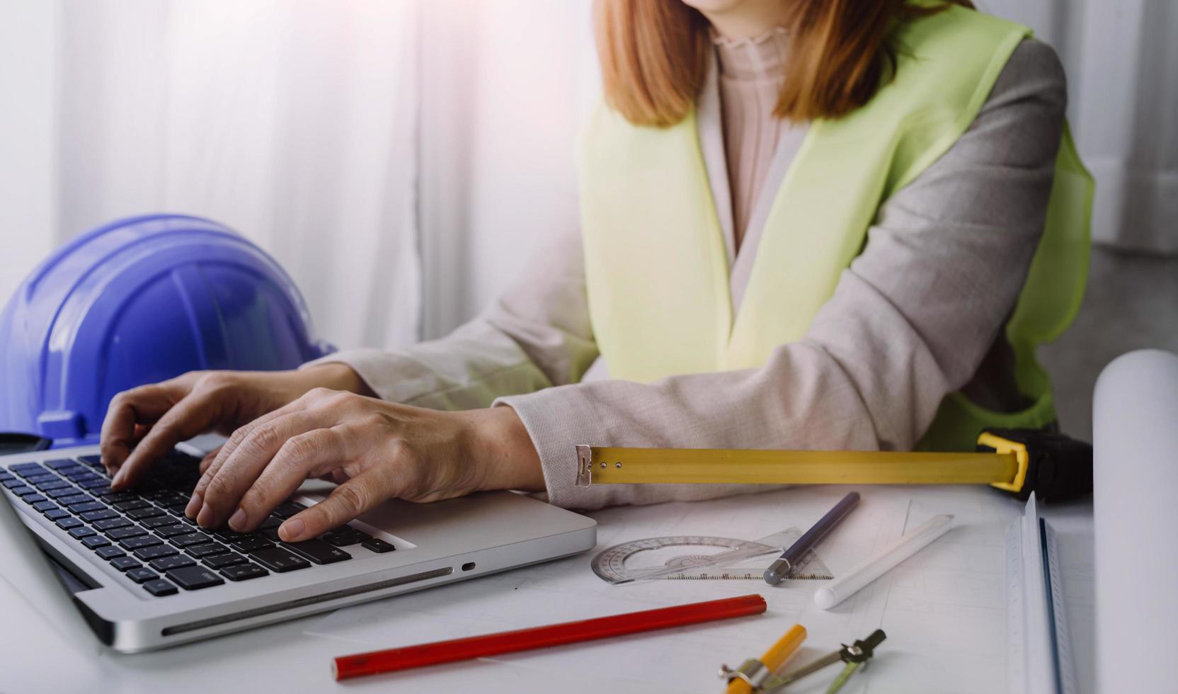 twee collega's bespreken gegevens werken en tablet, laptop met op architectonisch project op bouwplaats aan balie in kantoor foto