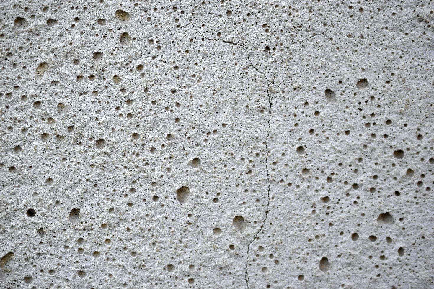 grijze achtergrond van een betonnen muur met gaten en scheuren. mooie gestuukte muur van het huis. foto
