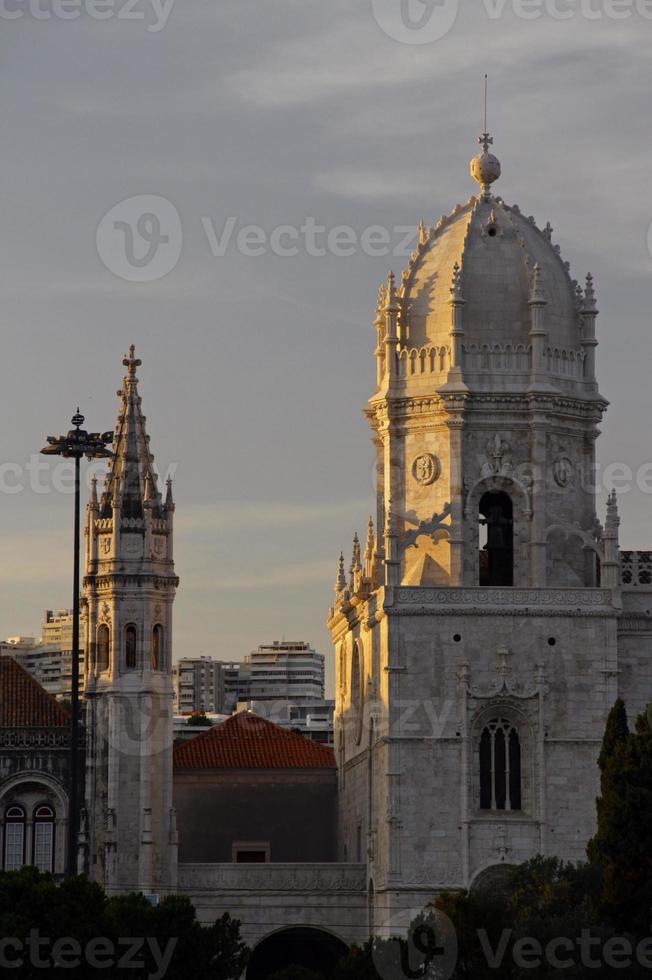 de ondergaande zon werpt gouden licht op de kerk van santa maria in lissabon, portugal foto
