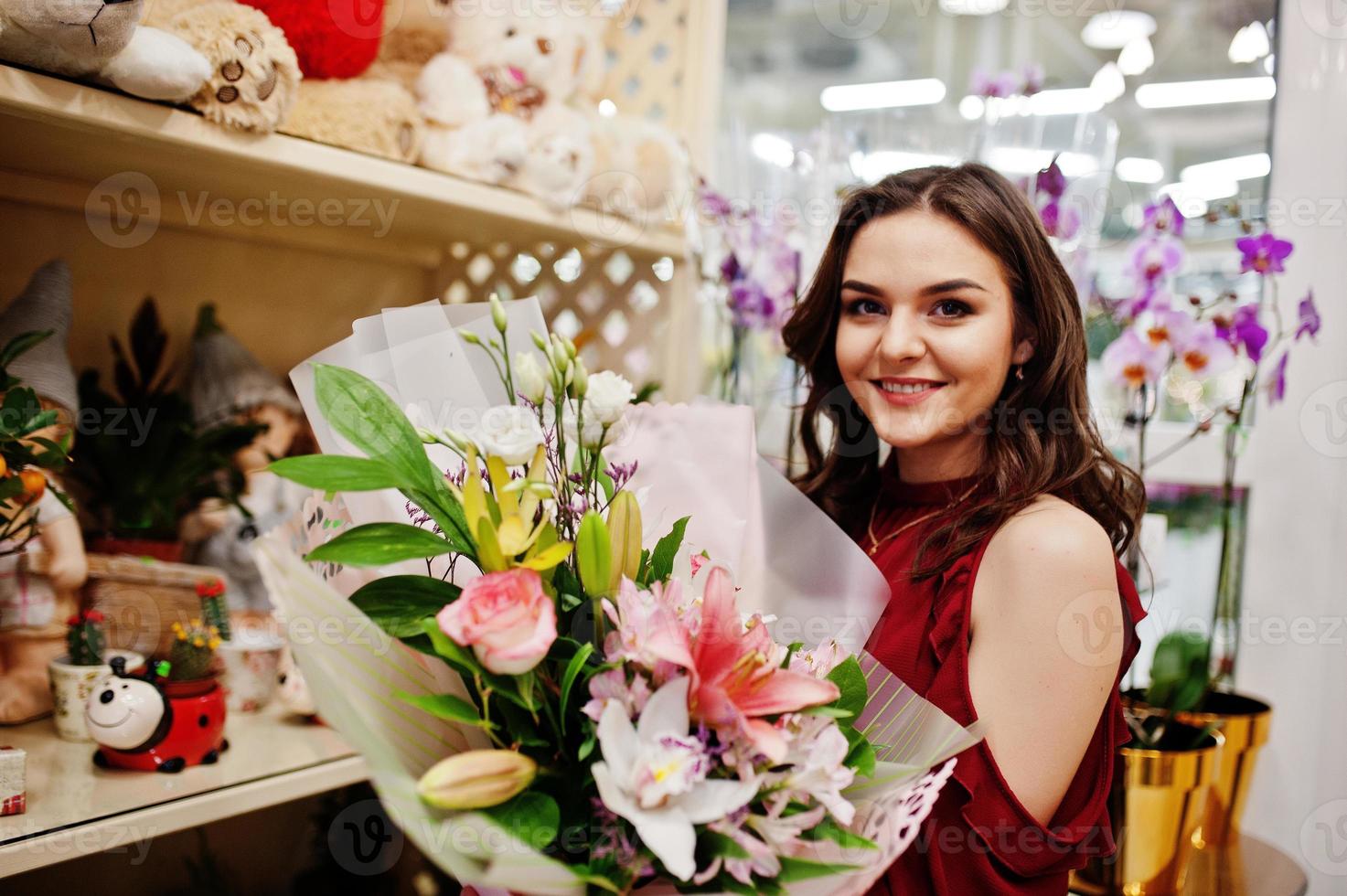 brunette meisje in het rood bloemen kopen bij bloemenwinkel. foto