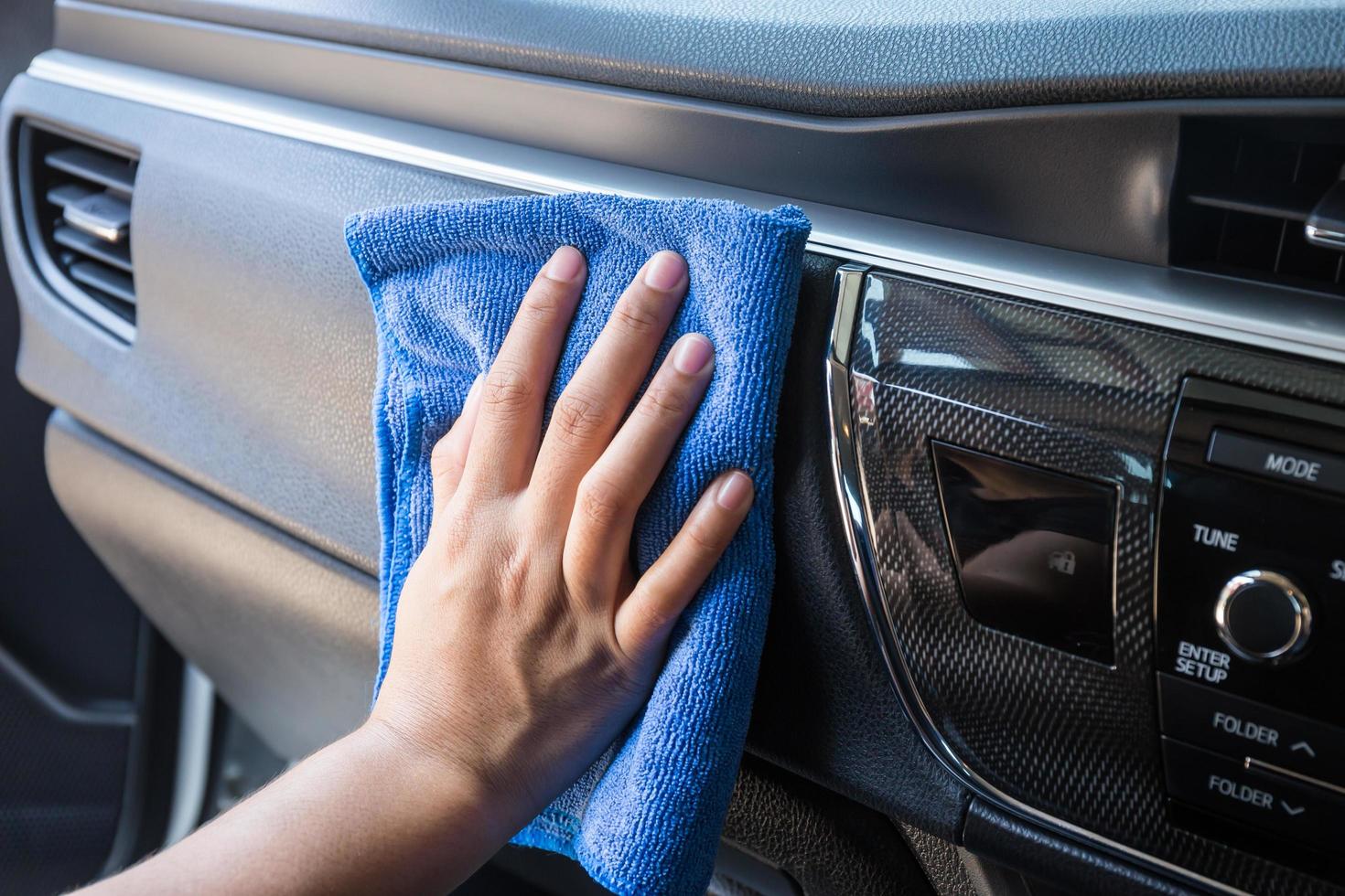 hand met microvezeldoek die interieur moderne auto schoonmaakt. foto