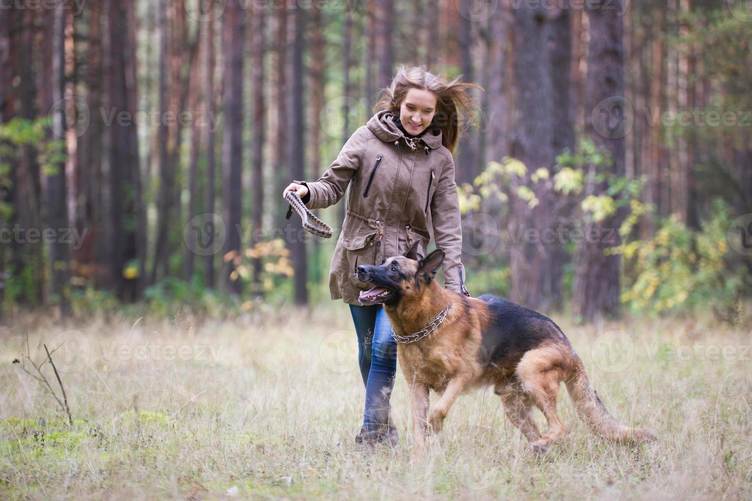 jonge aantrekkelijke vrouw die met Duitse herdershond buiten in het herfstpark speelt foto