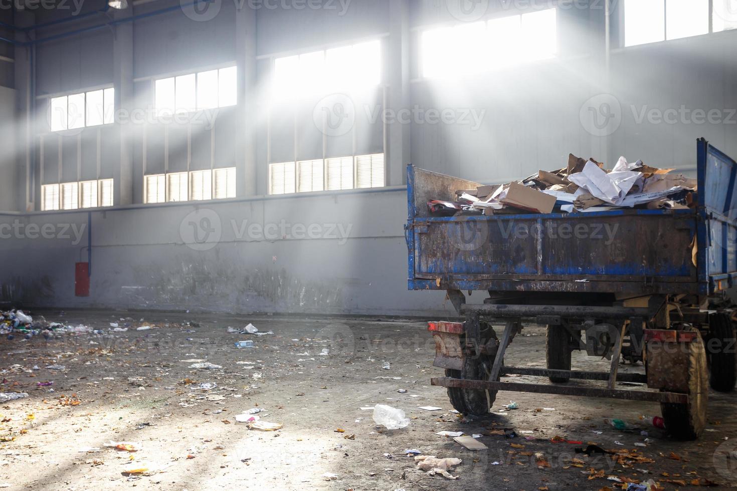 afvalsorteer- en recyclingwerkplaats met aanhanger bij de afvalverwerkingsfabriek met zonnestralen. gescheiden afvalinzameling. recycling en opslag van afval voor verdere verwijdering. foto