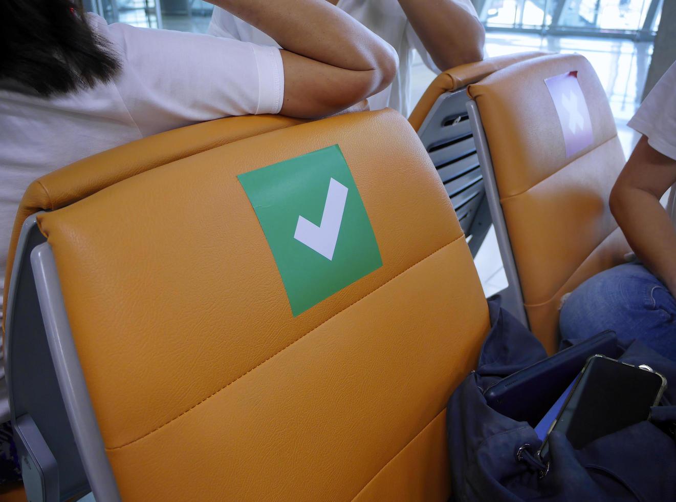 vrouwelijke reiziger zit met persoonlijke tas en brengt vrije tijd door met kletsen tijdens het wachten op het instappen in de luchthavenpoort foto