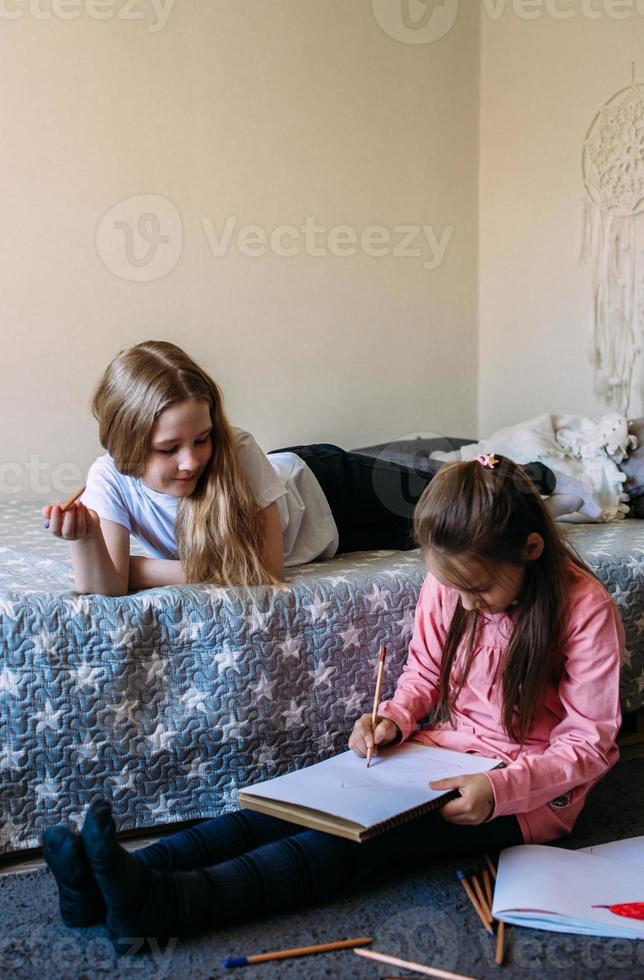 twee vriendinnen spelen thuis, tekenen met potloden en viltstiften en hebben plezier foto