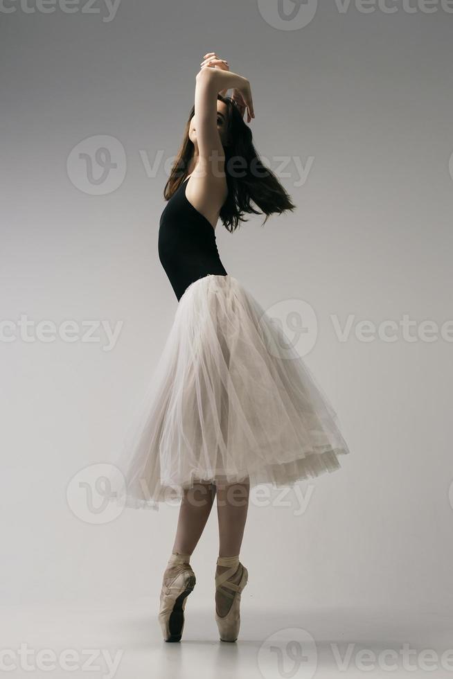 ballerina in bodysuit en witte rok improviseert klassieke en moderne choreografie in een fotostudio foto