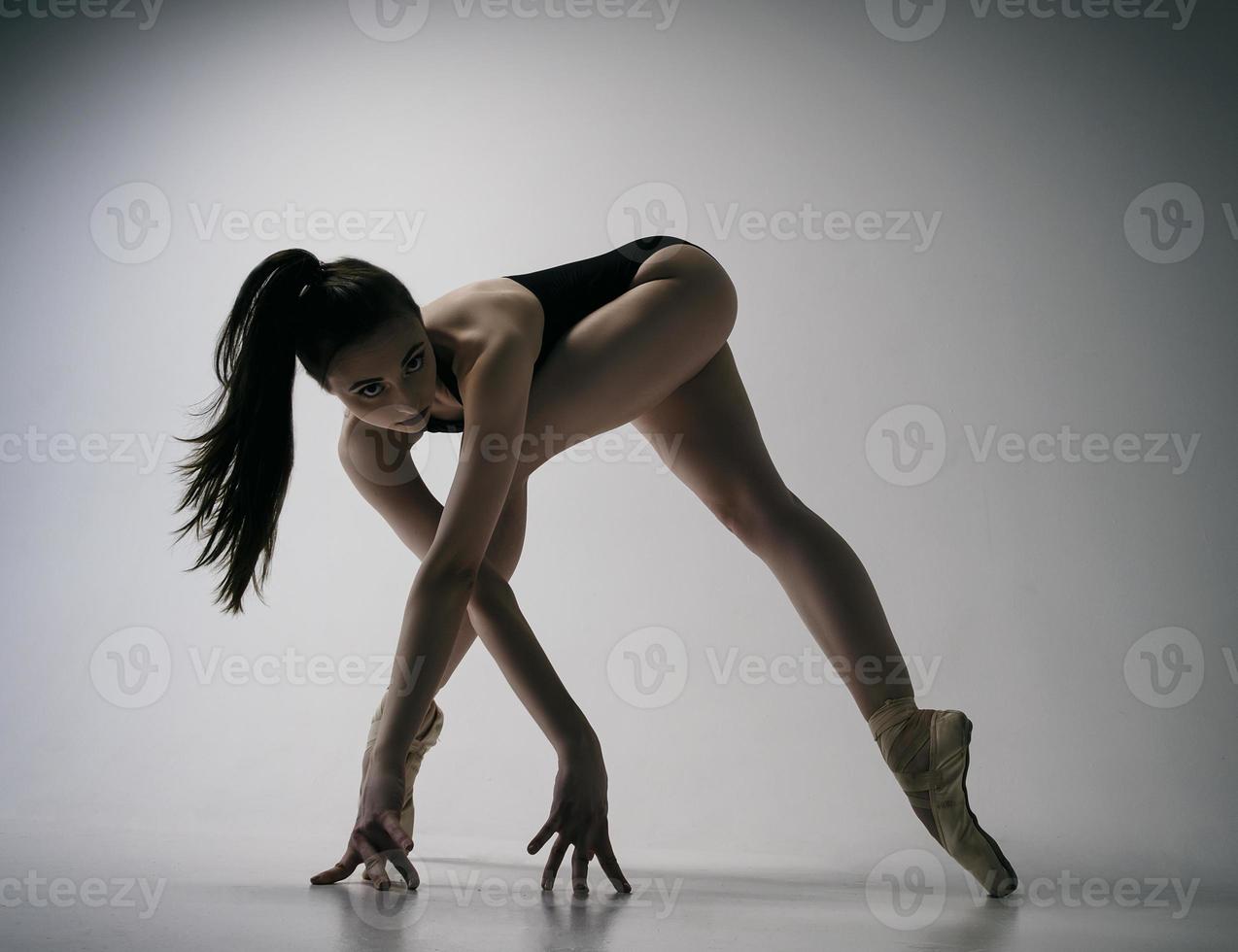 een ballerina in een bodysuit en een witte rok improviseert klassieke en moderne choreografieën in een fotostudio foto