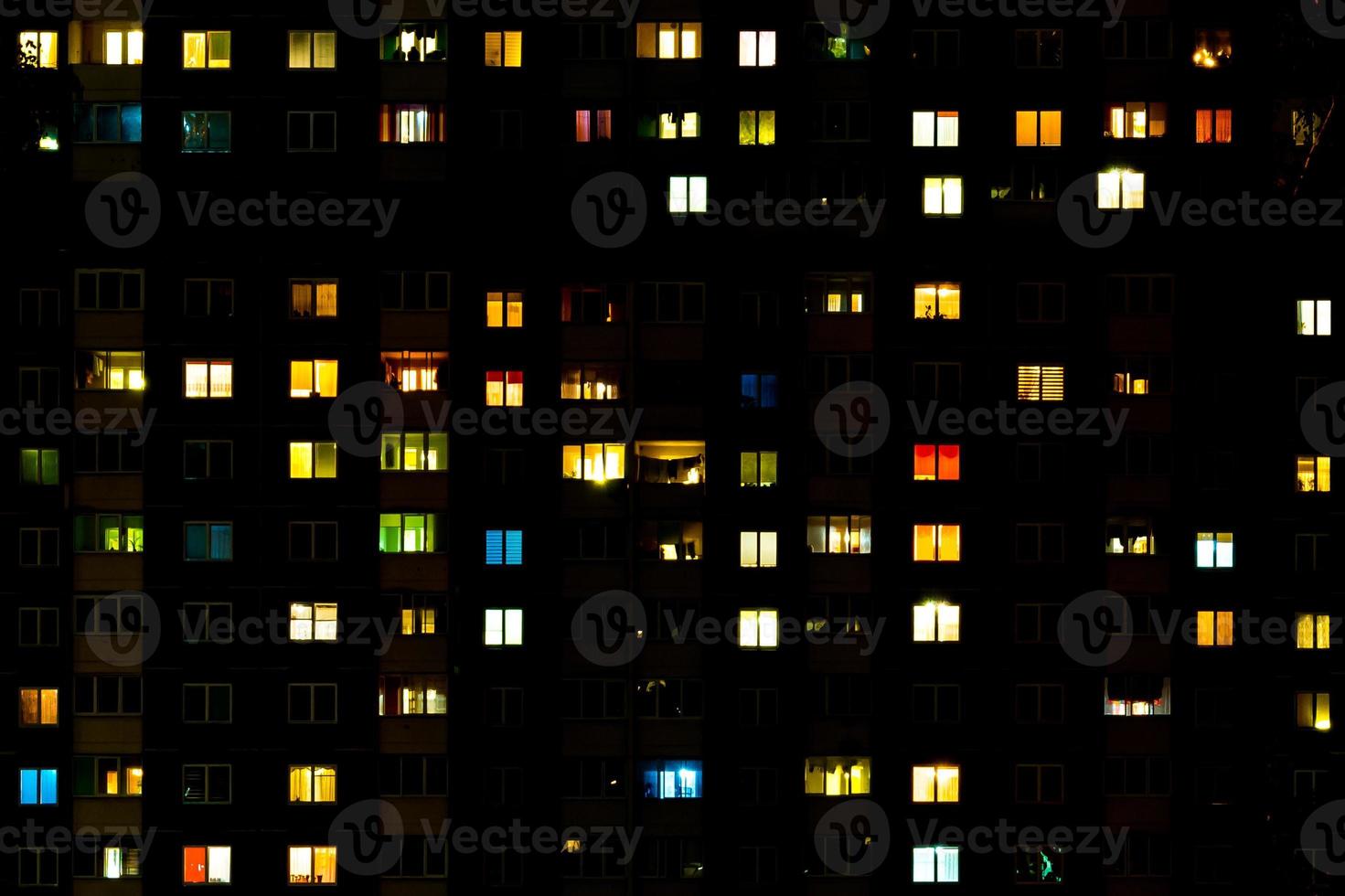 plat nachtpanorama van veelkleurig licht in ramen van gebouwen met meerdere verdiepingen. leven in de grote stad foto