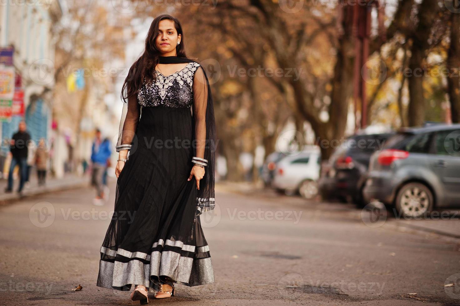 vrij indisch meisje in zwarte saree-jurk poseerde buiten in de herfststraat. foto