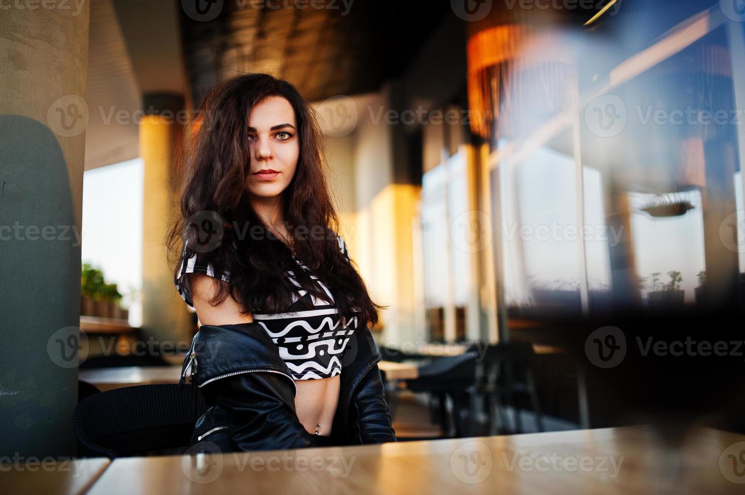 jonge krullende vrouw genieten van haar wijn in een bar. foto