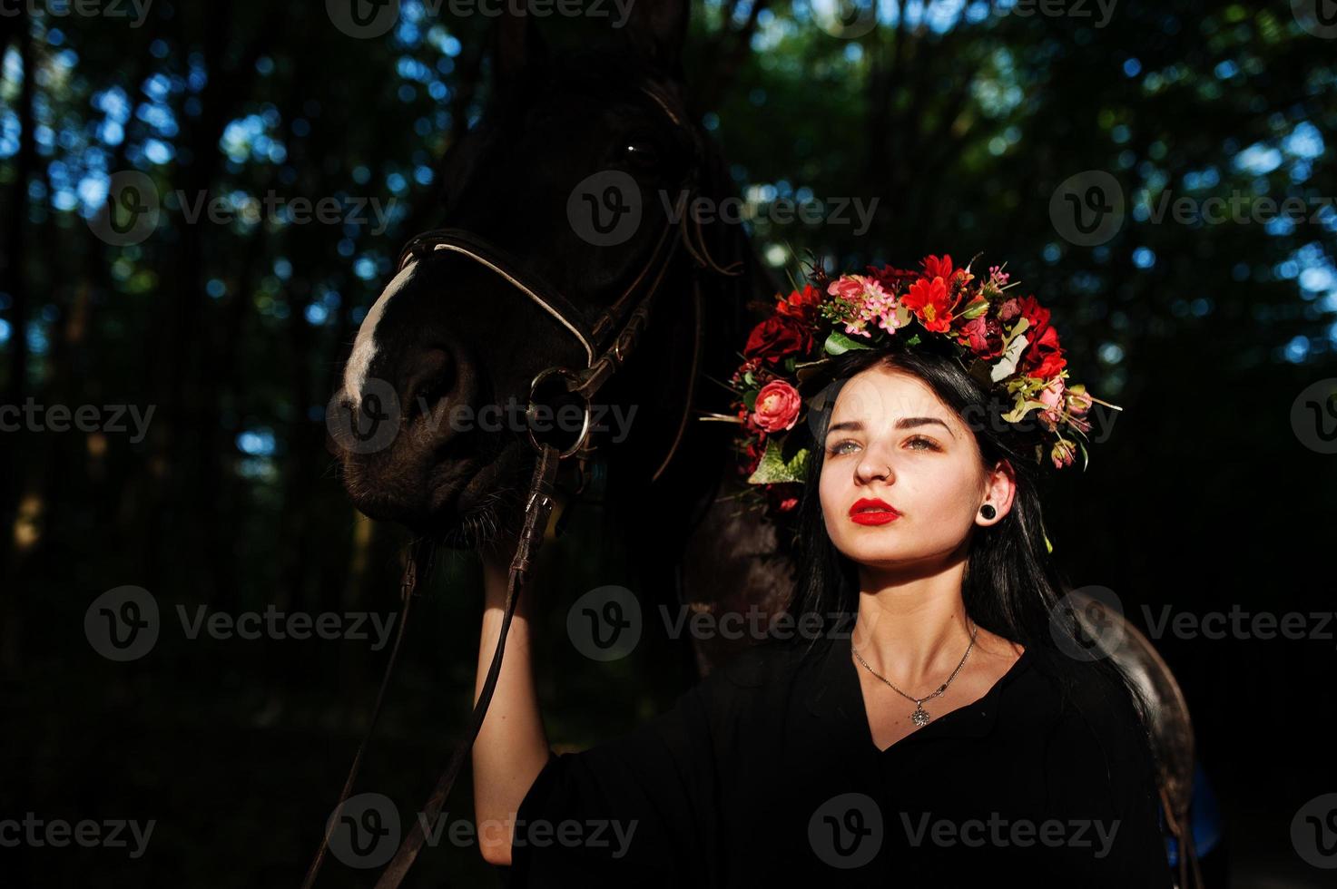 mystieke meisje in krans slijtage in zwart met paard in hout. foto