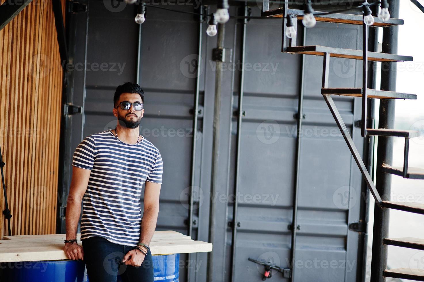 knappe lange Arabische baard man model op gestript shirt buiten geposeerd. modieuze Arabische man bij zonnebril. foto