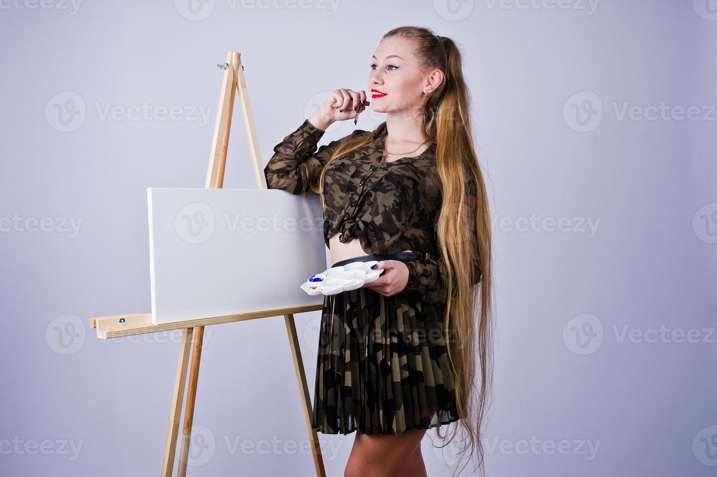 mooie vrouw kunstenaar schilder met borstels en olie canvas poseren in studio geïsoleerd op wit. foto