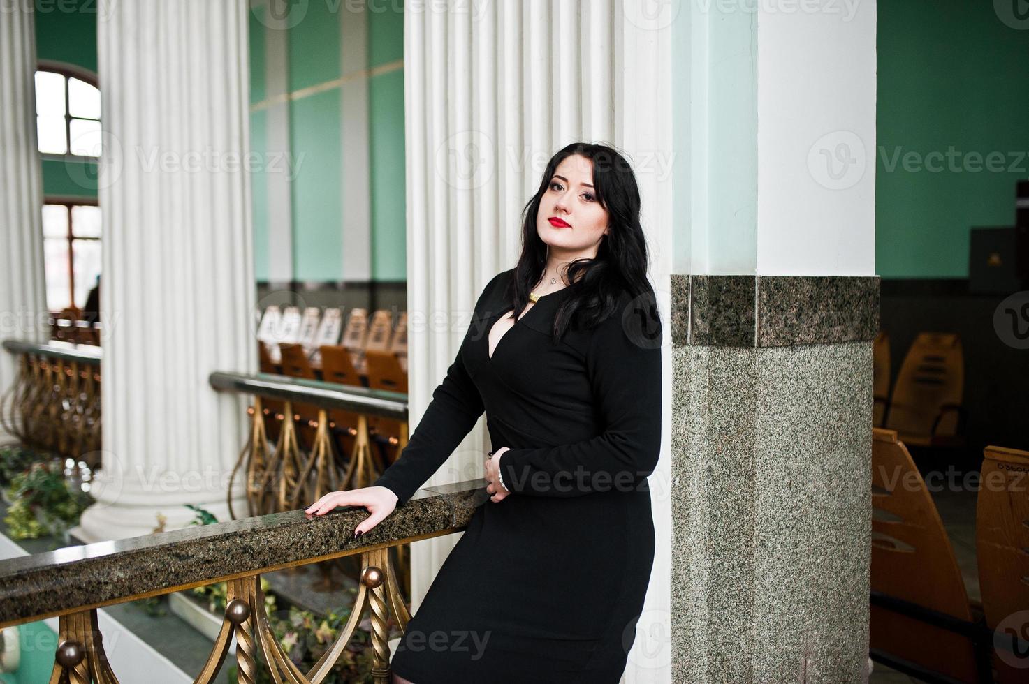 brunette meisje in zwarte jurk in treinstation binnen. foto