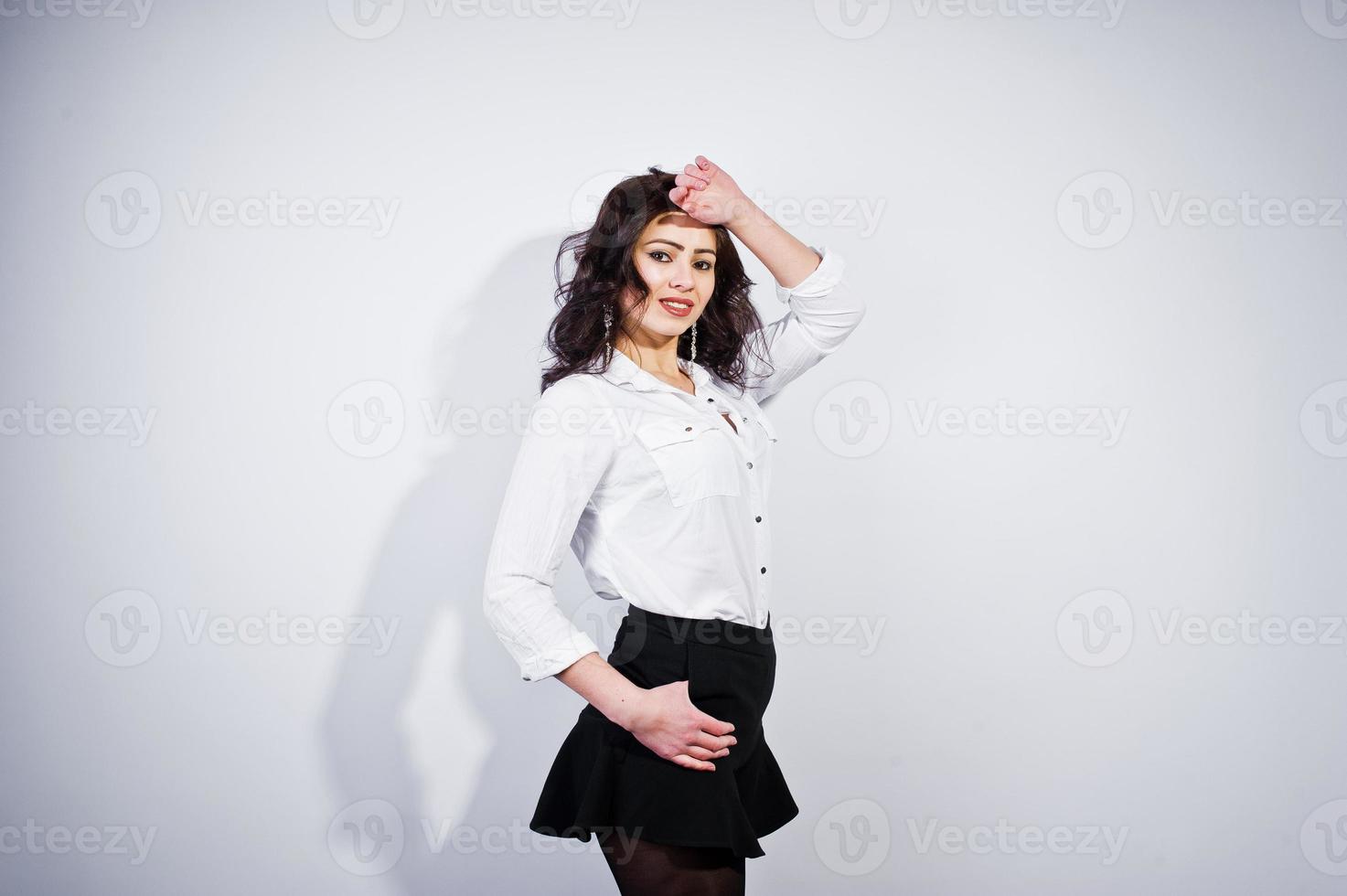 studio portret van brunette meisje in witte blouse op witte achtergrond. foto