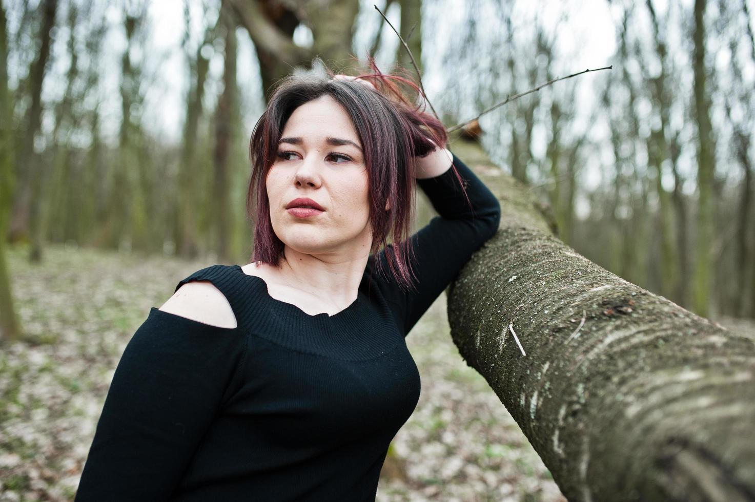 portret van brunette meisje in zwarte jurk op lente hout. foto