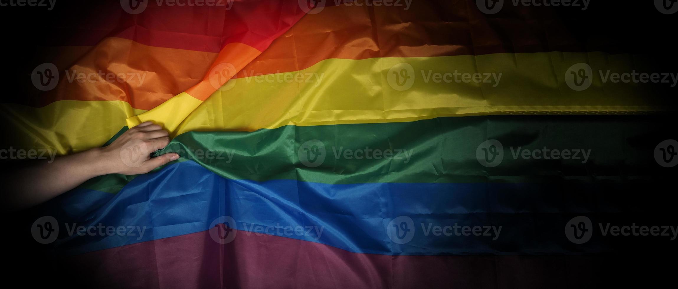 LGBT-trotsvlag op zwarte achtergrond. LGBT-regenboogvlag in homohand. foto