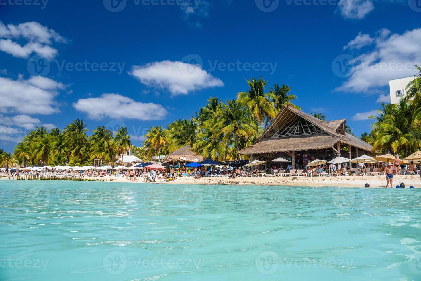 mensen zonnebaden op het witte zandstrand met parasols, bungalowbar en kokospalmen, turquoise Caribische zee, eiland Isla Mujeres, Caribische Zee, Cancun, Yucatan, Mexico foto