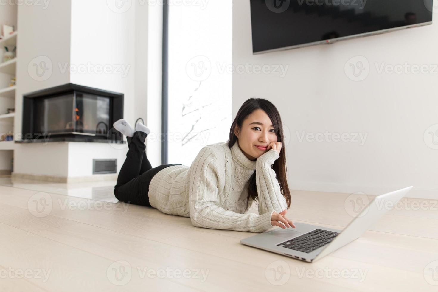 jonge aziatische vrouw die laptop op de vloer met behulp van foto