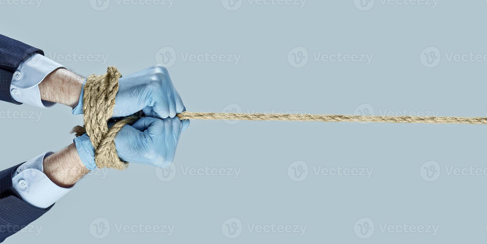 zakenman trekken en band vastgebonden met touw. concept zakelijke handen zijn vastgebonden met een touw. concept zakelijke handen zijn gebonden door een verbod op werk. foto