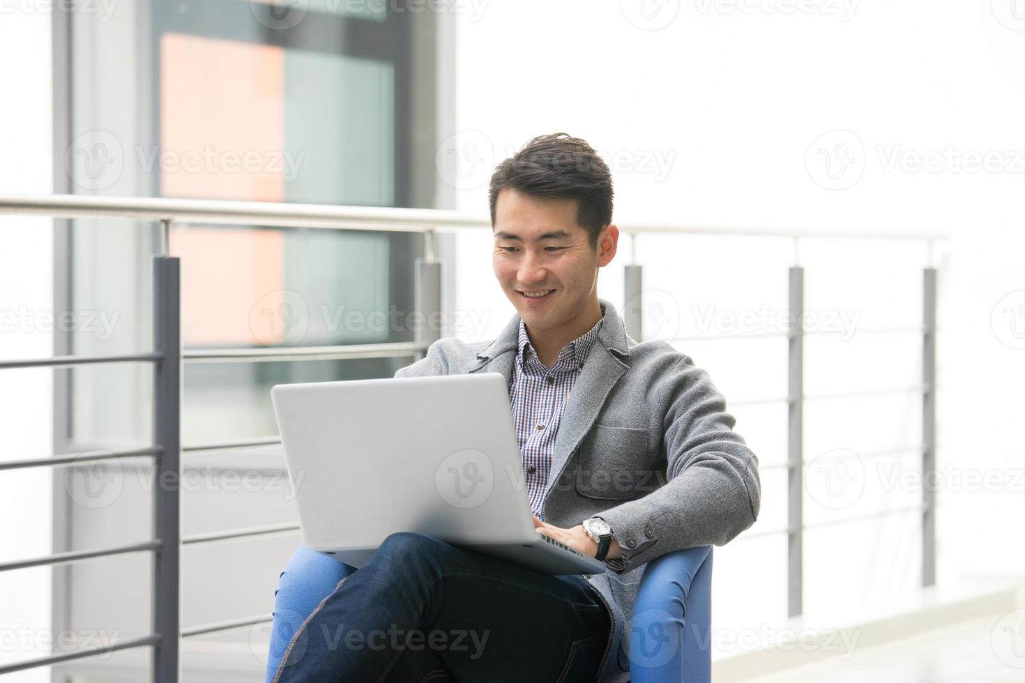 jonge Aziatische zakenman met behulp van tablet, mobiele telefoon op kantoor foto