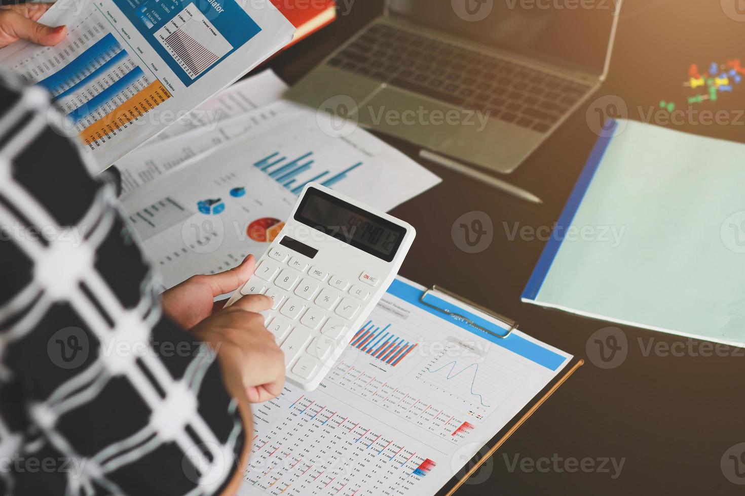 het boekhoudconcept van een zakenvrouw werkt aan het gebruik van een rekenmachine om kantoorsaldi te berekenen. foto