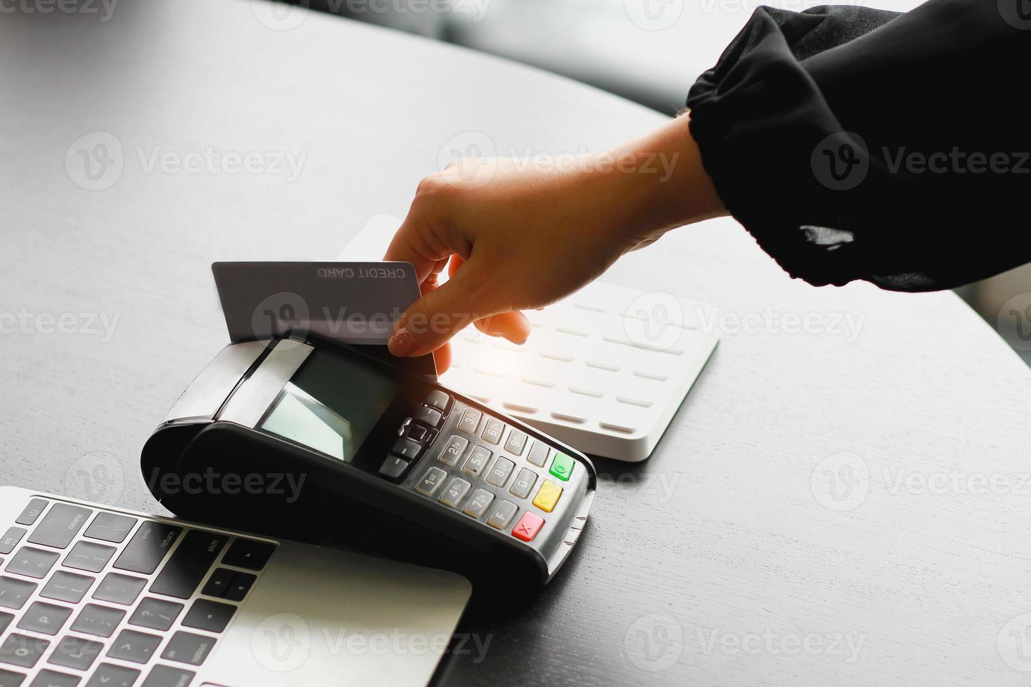 een vrouw die een hand-creditcard-veegmachine gebruikt om producten in de winkel te verkopen. concept van uitgaven via creditcard. foto