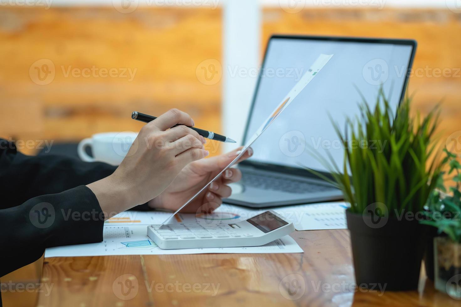 marketing, financieel, boekhouding, planning, zakenvrouwen analyseren bedrijfsresultaten en winst met grafiekstatistieken. gebruik een laptop en een rekenmachine om het saldo van het bedrijf te berekenen. foto