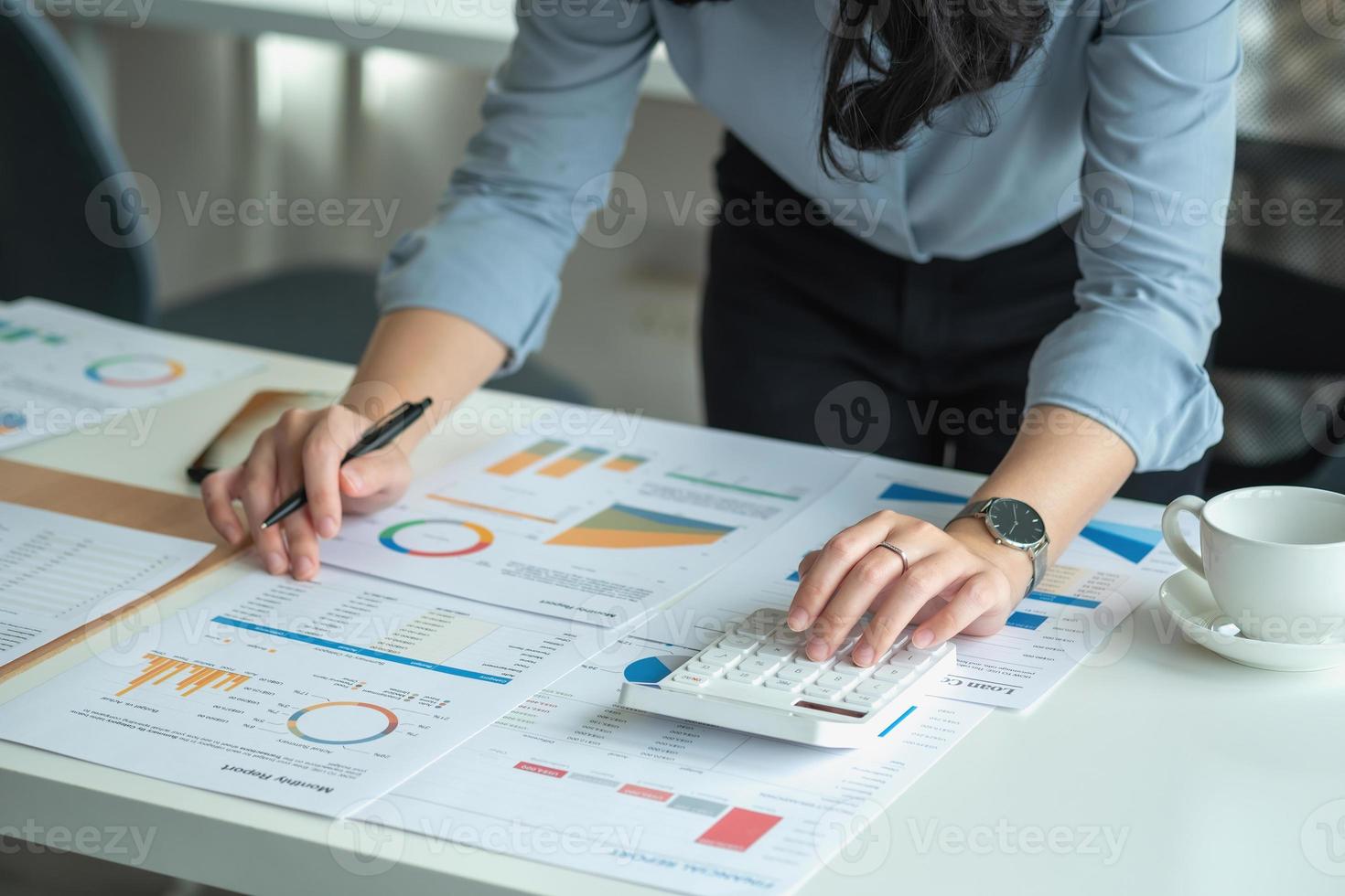 portret van een vrouwelijke accountant die een rekenmachine en laptop gebruikt om het saldo te berekenen met grafieken voor klanten. foto