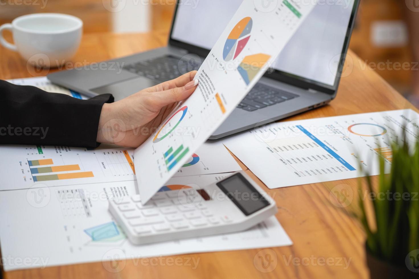 marketing, financieel, boekhouding, planning, zakenvrouwen analyseren bedrijfsresultaten en winst met grafiekstatistieken. gebruik een laptop en een rekenmachine om het saldo van het bedrijf te berekenen. foto